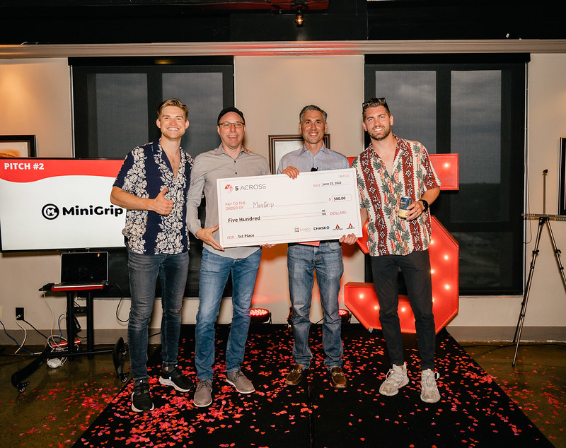 MiniGrip wins 5 Across June Startup Pitch Competition Founders of MiniGrip hold a giant check for $500 after winning the 5 Across June Pitch Competition
