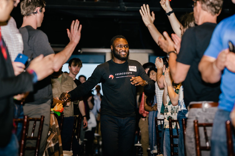 Dr. Stevens Bonhomme runs down the aisle at Awesome Inc's 5 Across Pitch Competition